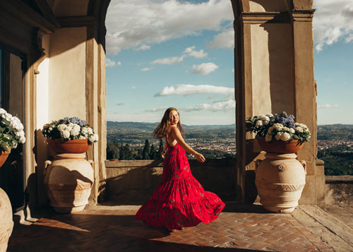 woman in a red dress twirling on a terrace in Tuscany